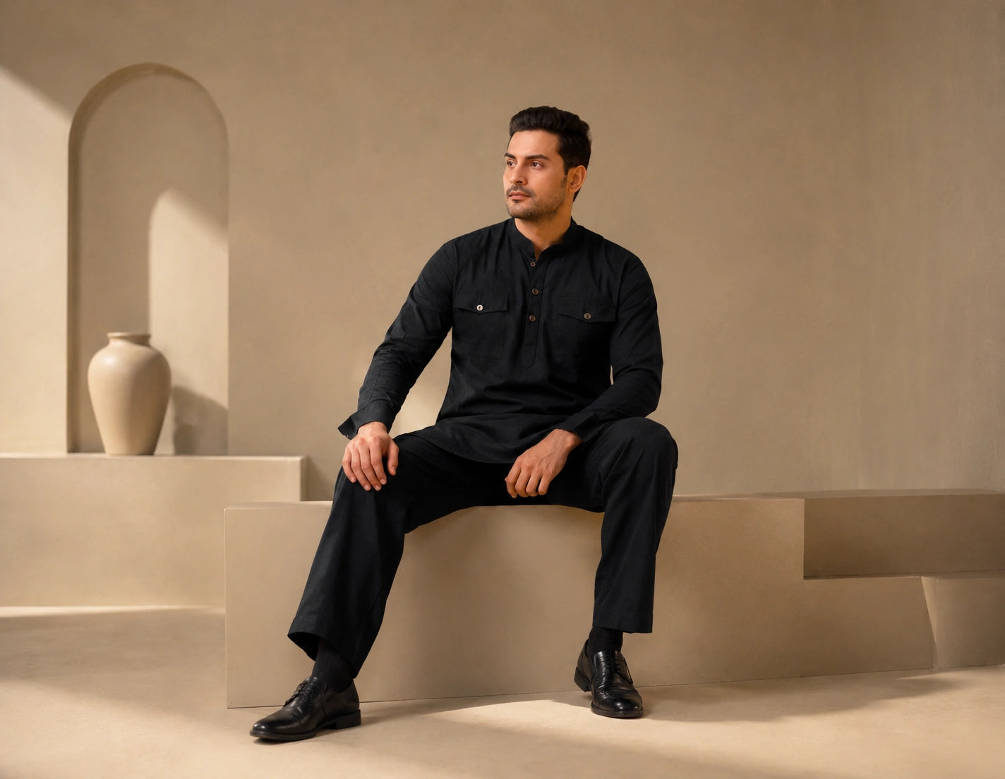 Male model wearing a modern black ethnic kurta and relaxed trousers by ETHNOIR in a minimalist studio setting.